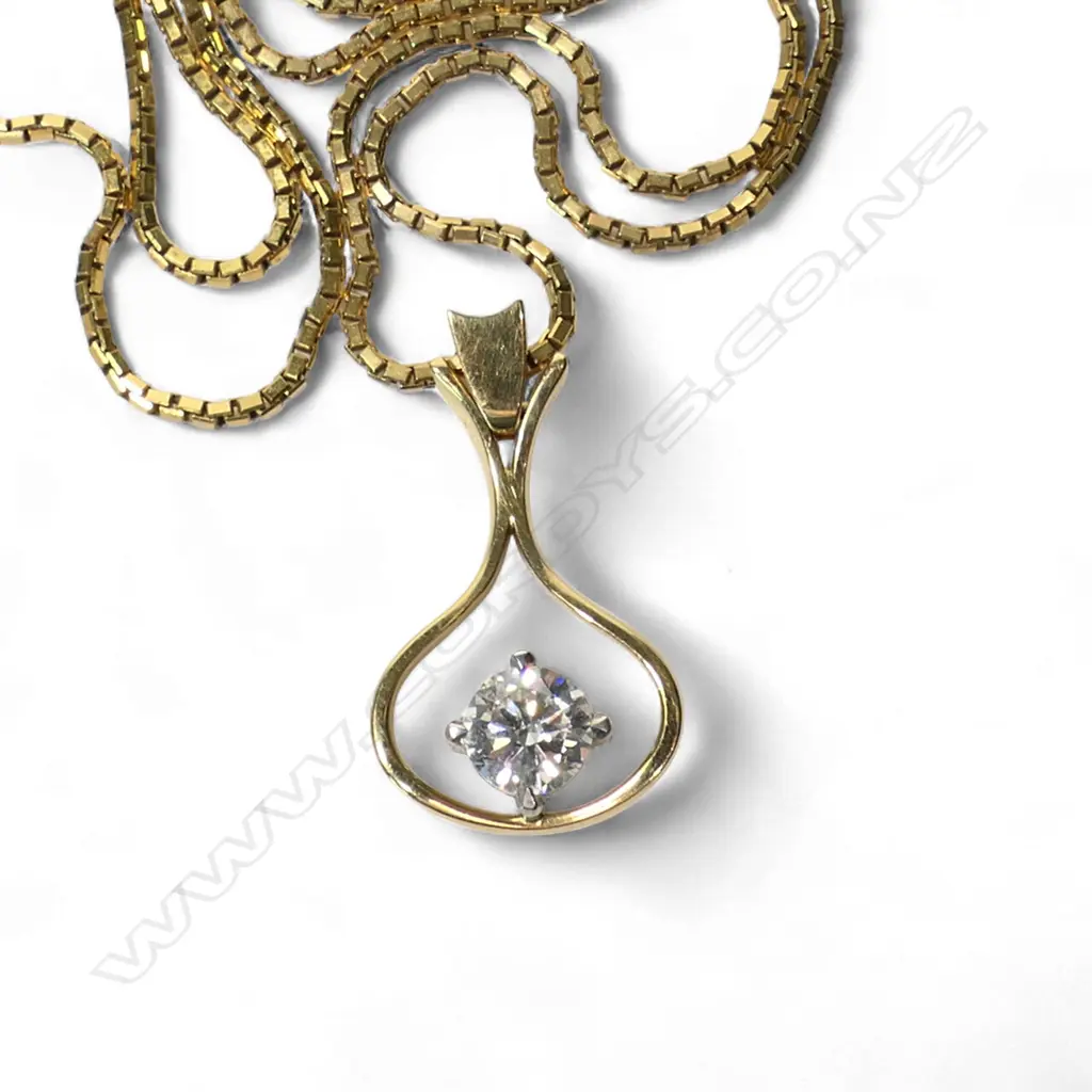 An 18ct gold and diamond pendant a 0.56ct round brilliant cut diamond (Colour G-H, Clarity VS) claw set in white gold to the centre of a wide drop shaped ribbon surround with swing hinged bale. With a fine 9ct gold box link chain. Valuation available. 4.80gms. Image 1++