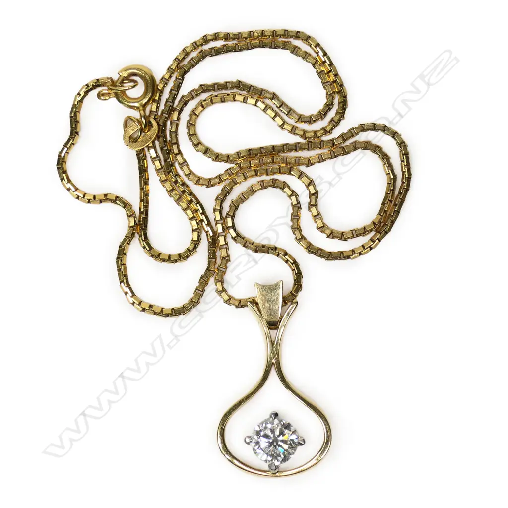 An 18ct gold and diamond pendant a 0.56ct round brilliant cut diamond (Colour G-H, Clarity VS) claw set in white gold to the centre of a wide drop shaped ribbon surround with swing hinged bale. With a fine 9ct gold box link chain. Valuation available. 4.80gms. Image 1++