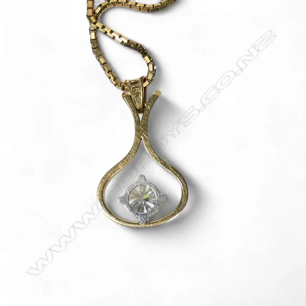 An 18ct gold and diamond pendant a 0.56ct round brilliant cut diamond (Colour G-H, Clarity VS) claw set in white gold to the centre of a wide drop shaped ribbon surround with swing hinged bale. With a fine 9ct gold box link chain. Valuation available. 4.80gms. Image 1++