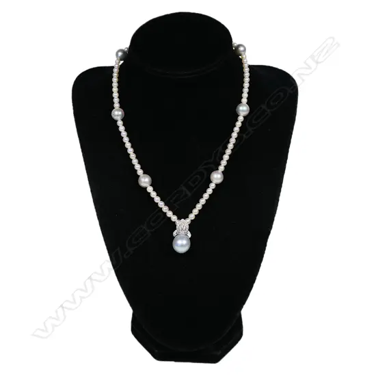 A pearl and diamond set necklace - a single strand of seventy-six 4mm Akoya type cultured pearls (white-pinkish with silver overtones and good lustre), with seven 10mm South Sea pearls (greyish-bluish with good lustre and moderate blemishes), interspersed with the smaller pearls, with a suspended 18ct white gold Bishop's mitre design pave set with diamonds supporting a 12mm bluish grey South Sea pearl. TDW. 0.31ct. The white gold clasp incorporated into one of the South Sea pearls. 39cm long