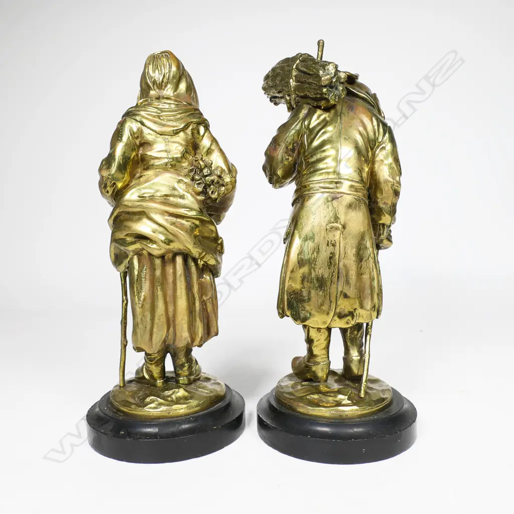 A pair of 19thC gilt bronze statuettes of a man and woman carrying bundles of faggots - each eldery character in patched and repaired attire, he wears a bicorn hat. Both on circular black slate bases. Unsigned. H.310mm, Image 1++