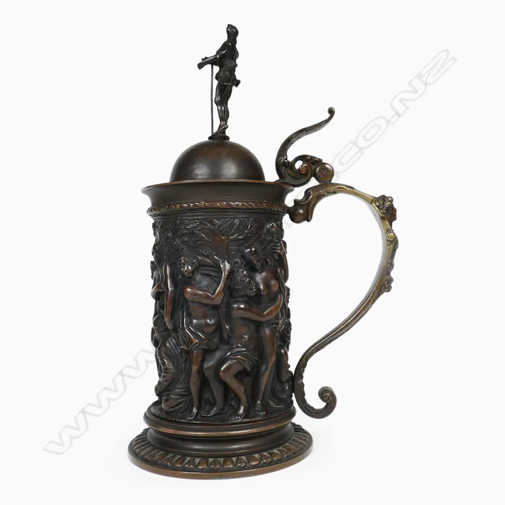 A sculptural bronze tankard - decorated in relief of a Bacchanalian feast, figural handle and male figure to the lid. H.270mm. Image 1++