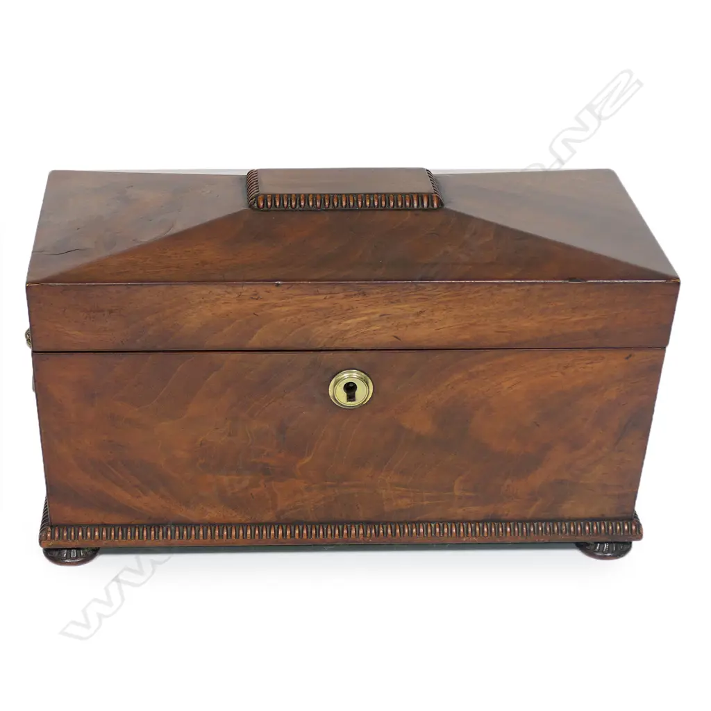 A Regency flame mahogany tea caddy - of sarcophagus form with lion mask captured ring handles, fitted interior with twin lidded compartments and period cut glass mixing bowl. 320 x 180 x 190mm, Image 1++