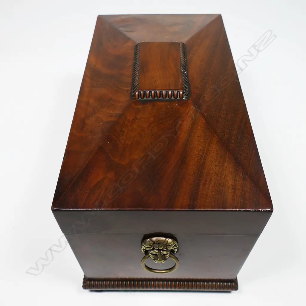 A Regency flame mahogany tea caddy - of sarcophagus form with lion mask captured ring handles, fitted interior with twin lidded compartments and period cut glass mixing bowl. 320 x 180 x 190mm, Image 1++