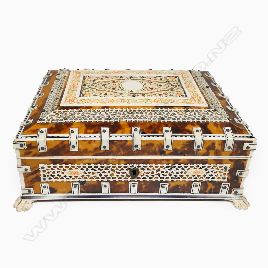 An antique vizagapatam tortoiseshell and ivory box - the ivory with engraved and coloured decoration, the interior lined and with compartments, mirror to the lid. Raised on paw feet. 210 x 160 x 100mm. Image 1++