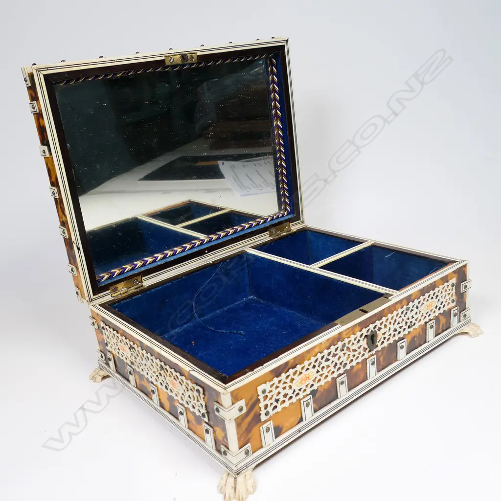 An antique vizagapatam tortoiseshell and ivory box - the ivory with engraved and coloured decoration, the interior lined and with compartments, mirror to the lid. Raised on paw feet. 210 x 160 x 100mm. Image 1++