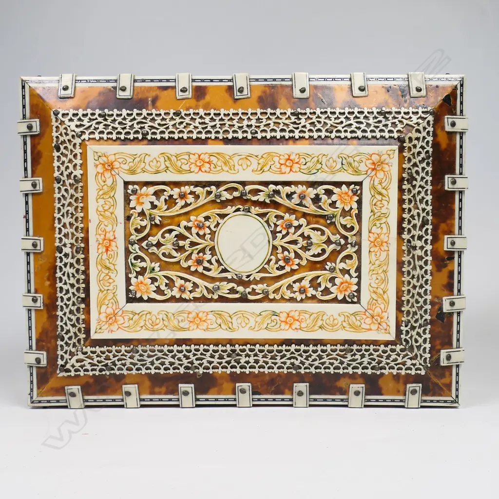 An antique vizagapatam tortoiseshell and ivory box - the ivory with engraved and coloured decoration, the interior lined and with compartments, mirror to the lid. Raised on paw feet. 210 x 160 x 100mm. Image 1++