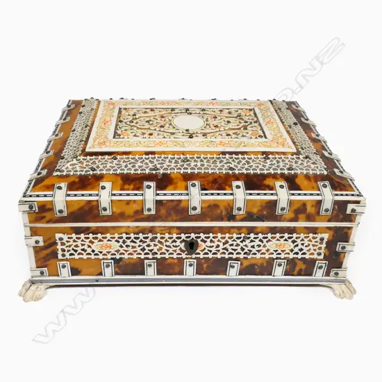 An antique vizagapatam tortoiseshell and ivory box - the ivory with engraved and coloured decoration, the interior lined and with compartments, mirror to the lid. Raised on paw feet. 210 x 160 x 100mm.