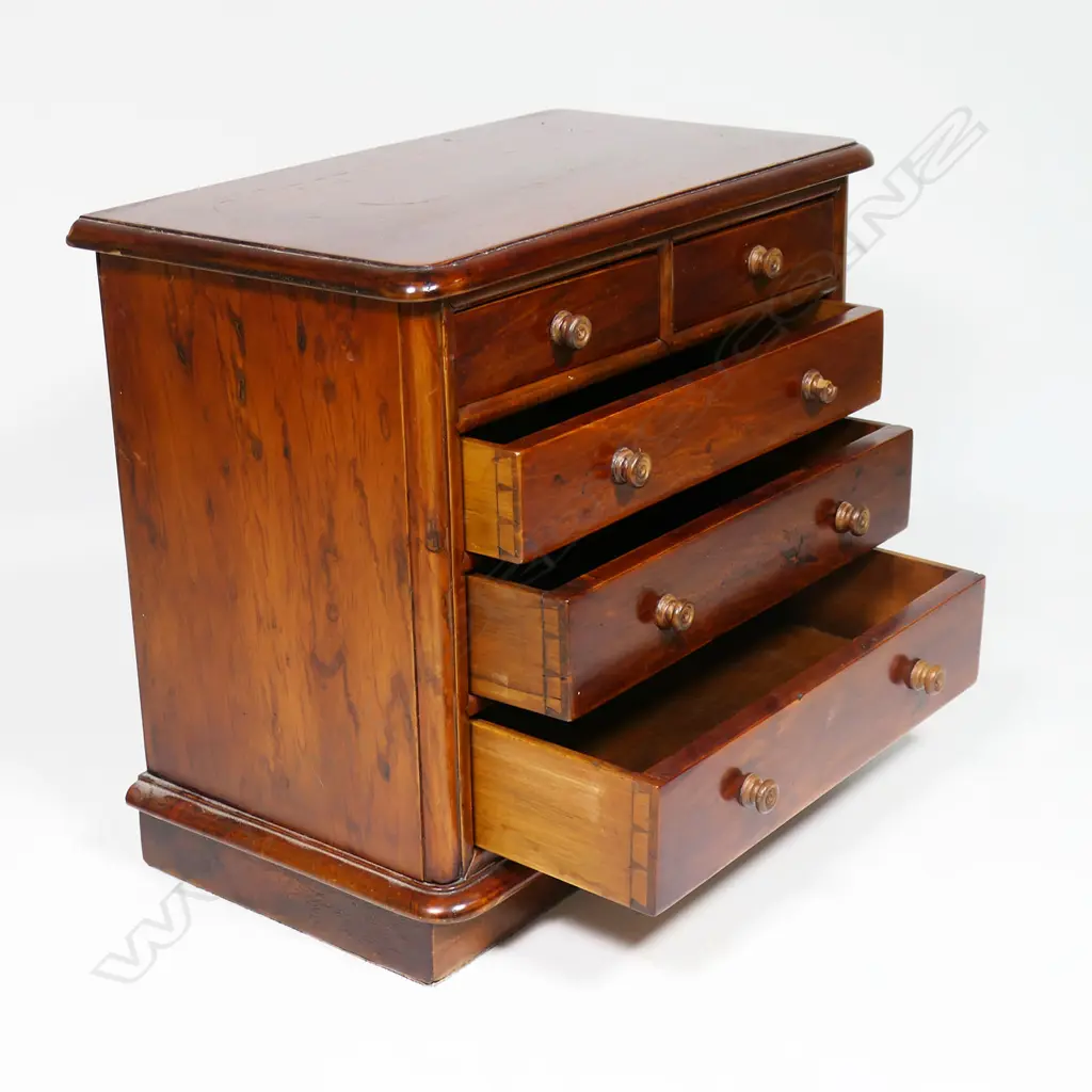 A late 19thC New Zealand colonial solid mottled kauri apprentice type chest - two short over three long graduating drawers, knob handles, one chipped, a similar replacement available. Plinth base, plain kauri top with thumb moulded edge. 360 x 200 x 330mm. Please note: The foot and back boards are later replacements Image 1++