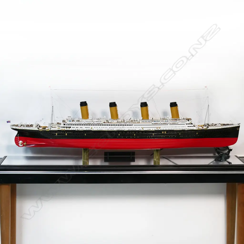 A model of RMS Titanic - on mirrored base and table, together with eight Titanic books and a jigsaw puzzle. L.1375mm. Image 1++