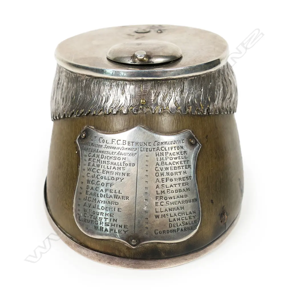 An historic Boer War presentation silver mounted horses hoof inkwell - the applied silver shield presentation engraved with multiple names including Lt. Col. F.C. Bethune Major, Major R.L.Walter and 31 other names. The silver top with missing attachment and small lidded inkwell above an applied silver mount modelled and engraved as horses hair. Silver horse shoe to the base. Image 1++