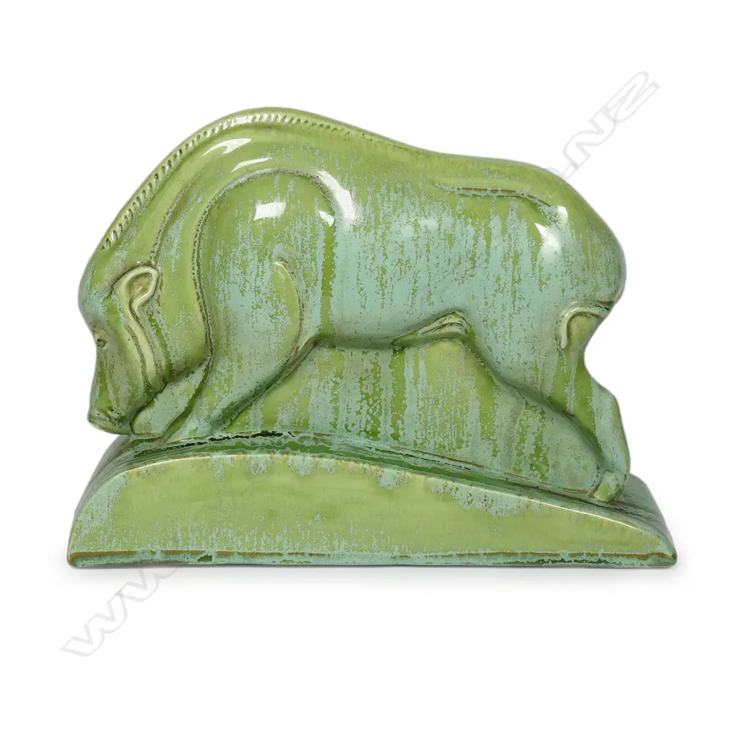 A Clarice Cliff Art Deco green art glaze boar sculpture - produced in 1936 for Wilkinson's Ltd. Stylised form, on a tapered curved base, the variable green glaze with pale matt and mid-green gloss highlights. L.246mm. H.174mm. Illustrated in Howard & Pat Watson's book 'collecting Art Deco Ceramics', Kevin Francis Publishers, London, 1993. Image 1++