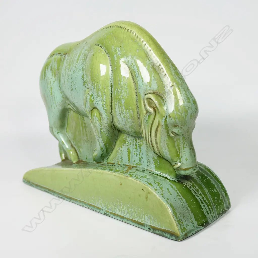 A Clarice Cliff Art Deco green art glaze boar sculpture - produced in 1936 for Wilkinson's Ltd. Stylised form, on a tapered curved base, the variable green glaze with pale matt and mid-green gloss highlights. L.246mm. H.174mm. Illustrated in Howard & Pat Watson's book 'collecting Art Deco Ceramics', Kevin Francis Publishers, London, 1993. Image 1++