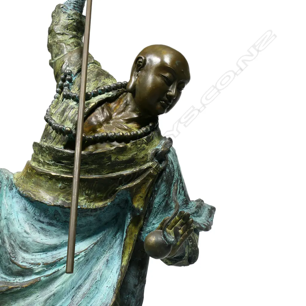 A highly decorative and energetic bronze of a bodhisattva Shaolin monk - wielding his khakkhara staff in his raised arm and manifesting a flaming pearl in his left hand, stamped under the hem of his flaring cloak with two undeciphered zhuanshu script seal marks. The surface treatments including cold painting and enhanced verdigris patination. The poised stance above rising and falling waves mirroring the Buddhist concept of finding balance and equanimity amidst change, the ebb and flow - life and death. H.1010mm, Image 1++