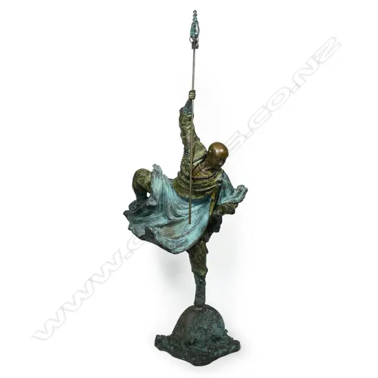 A highly decorative and energetic bronze of a bodhisattva Shaolin monk - wielding his khakkhara staff in his raised arm and manifesting a flaming pearl in his left hand, stamped under the hem of his flaring cloak with two undeciphered zhuanshu script seal marks. The surface treatments including cold painting and enhanced verdigris patination. The poised stance above rising and falling waves mirroring the Buddhist concept of finding balance and equanimity amidst change, the ebb and flow - life and death. H.1010mm,