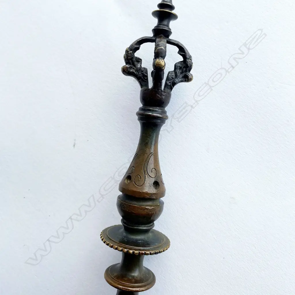 A Tibetan Buddhist kartika (ceremonial knife) on ornate axe shaft, 19thC - steel crescent blade set in bronze mounts incorporating swastika engraved octagon mount and vajra terminals on a double baluster knopped shaft. L.340mm. Image 1++