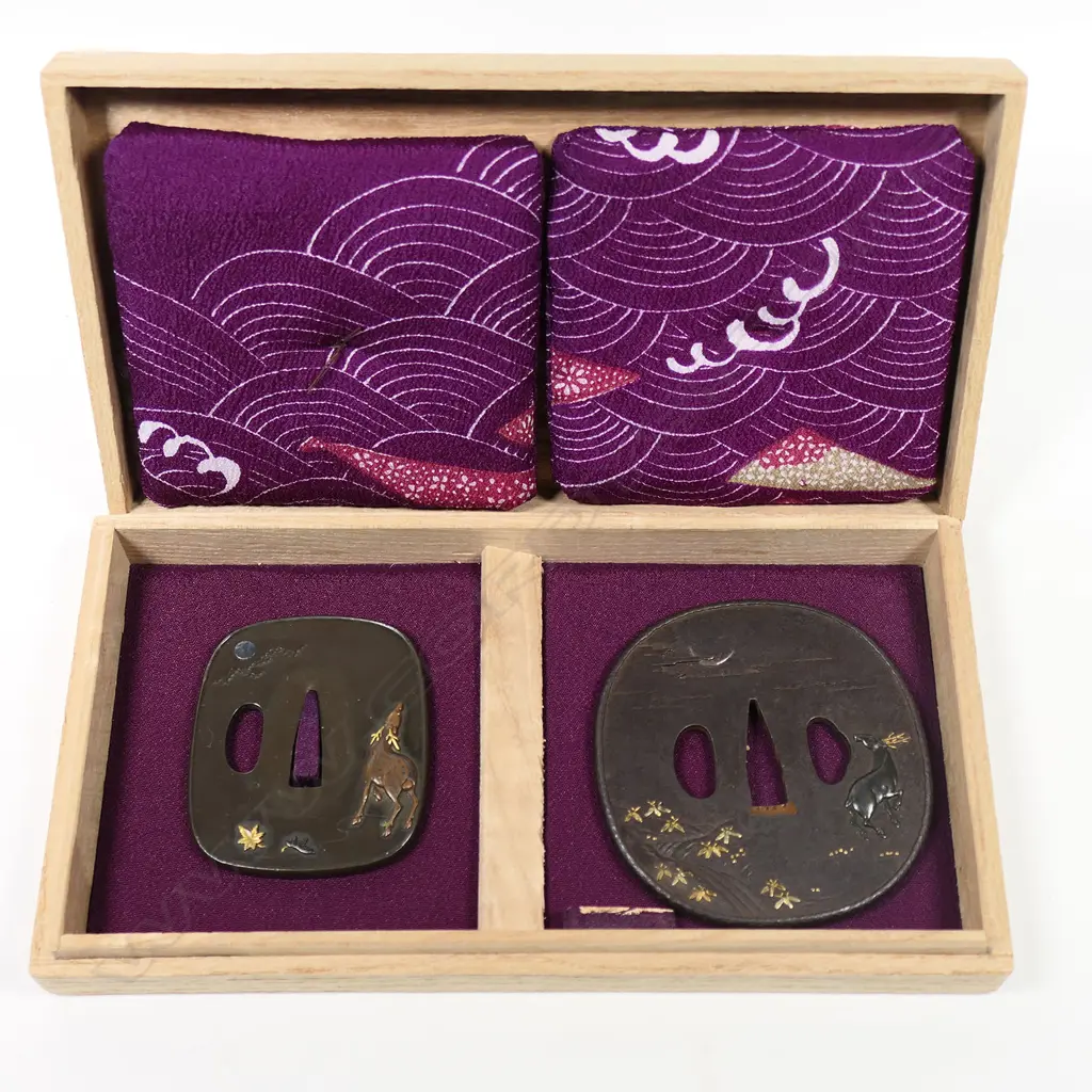 A superb pair of 19thC Daisho tsuba - the Dai in iron with raised rim showing a Shibuichi stag in relief by a river under a silver crescent moon, gold highlights on foliage to the front and reverse. The Sho in Shiboichi with raised deer in copper with gold antlers under a silver full moon behind clouds. Gold and Shakudo maple leaves on front and reverse. In fitted box. Image 1++