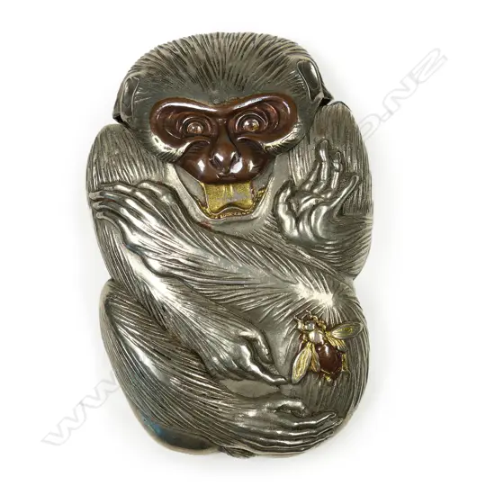 A c.1900 Japanese novelty white metal vesta case - as a monkey, its attention drawn to a bee on its leg. The bee and mouth highlighted in gilt and bronze overlay. H.65mm.