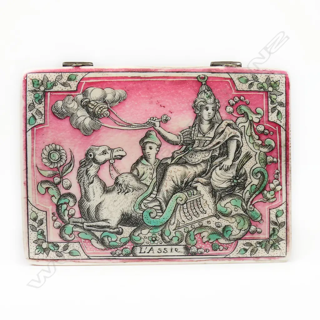 A French Lois XV painted Asian themed ivory gaming or card box - the lid with red and green stained incised scrimshaw like scene of a woman and attendant seated on a camel, entitled 'L'Assie' (Asia). The interior with decorative hinge and incised scene of a large rural building. The base with a heart decorated playing card. 80 x 60 x 15mm. Image 1++