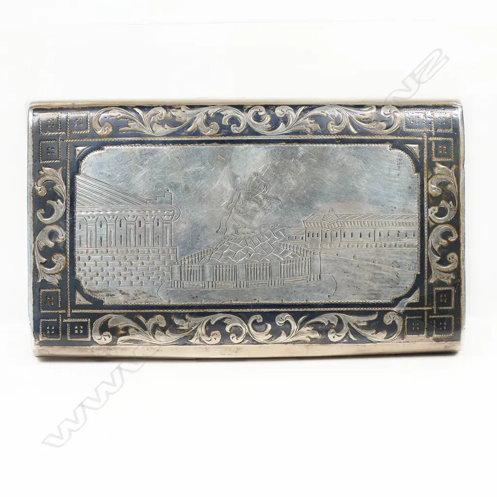 A 18thC Russian silver niello cigar case - of satchel form. The back engraved with a scene of a St. Petersburgh city monument framed by leafy scrolls. Lavishly gilded interior. Marks probably for the maker Fyodor Ivanof and for the assay master Aggey Grigori Svechin, Moscow 1862. W.120mm. 145gms. Image 1++