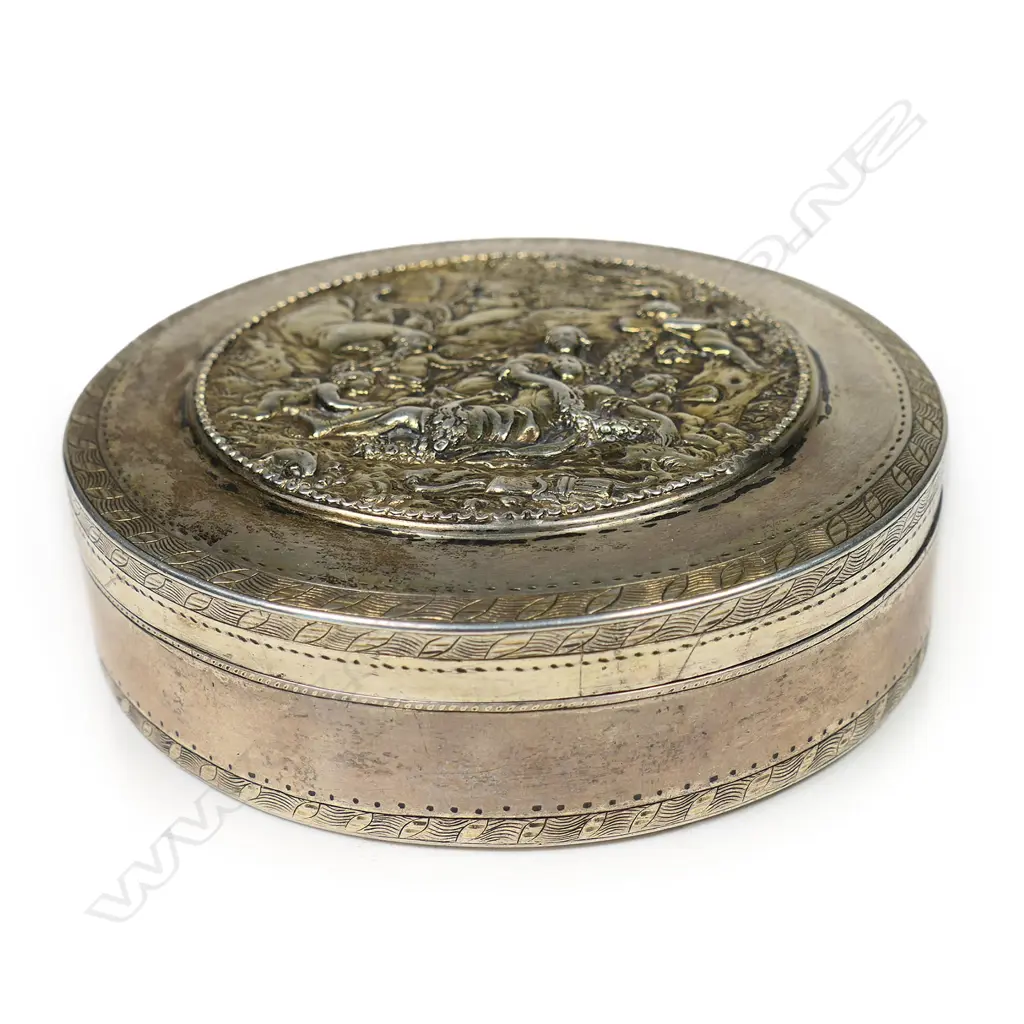 An 18thC Russian silver table box - the lid cast with a relief scene of two women in a treed landscape surrounded by cherubs. Fine engraved border bands. Stamped mark for 1786. Dia.90mm. 212gms. Image 1++