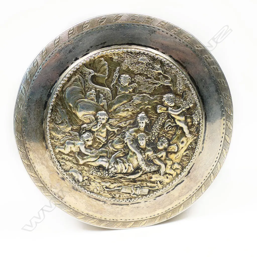 An 18thC Russian silver table box - the lid cast with a relief scene of two women in a treed landscape surrounded by cherubs. Fine engraved border bands. Stamped mark for 1786. Dia.90mm. 212gms. Image 1++