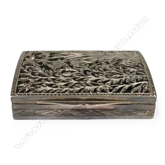 An early 20thC decorative silver box - the lid with elaborate fret cut reed, foliate and bird decorated scene jewelled with marcasite's (minor losses) and pink stones on black probably silk ground, geometric engraved Art Deco style decoration. 80 x 60 x 15mm. 118gms.