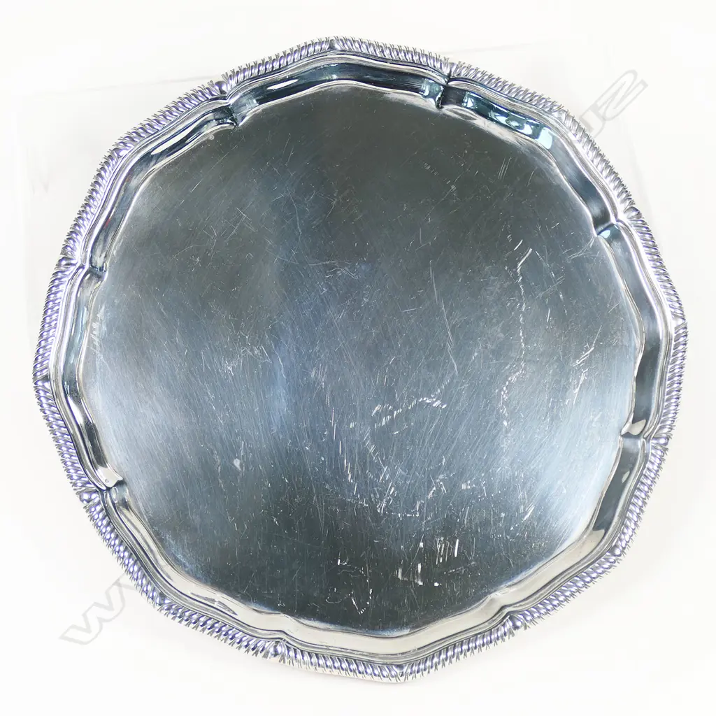 An early 1900s silver salver - gadrooned rim, plain centre, raised four ball and claw feet. London 1910 by Thomas Bradbury & Sons Ltd. 386gms. Dia.200mm. Image 1++