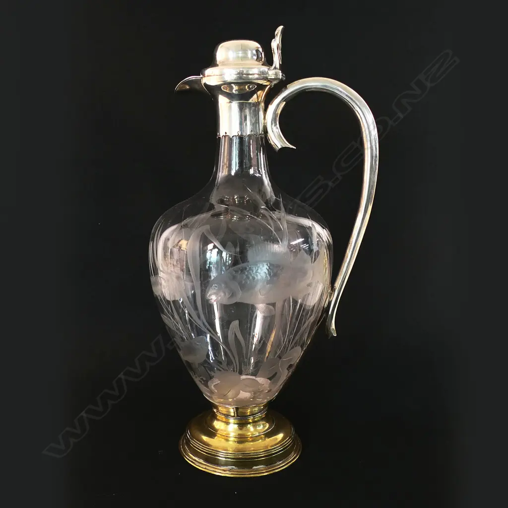 A silver and decorative fish themed cut glass wine ewer - with silver hinged lid, top mount with spout and handle. London 1876 by Jane Brownett & Alexander Jones. The ovoid body finely engraved with fish amongst reeds. On after market period brass steeped foot. H.340mm. Image 1++