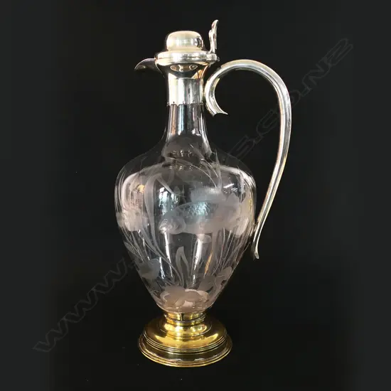 A silver and decorative fish themed cut glass wine ewer - with silver hinged lid, top mount with spout and handle. London 1876 by Jane Brownett & Alexander Jones. The ovoid body finely engraved with fish amongst reeds. On after market period brass steeped foot. H.340mm.