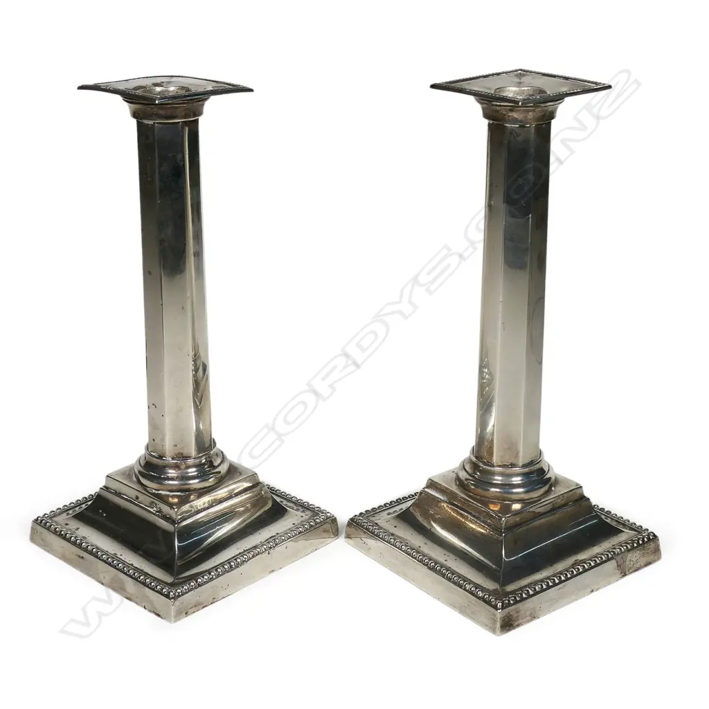 A pair of elegant silver column candlesticks, by Martin Hall & Co., Sheffield 1898 - of slightly tapering octagonal section, raised on bead edged ogee plinth bases and with conforming nozzles. H.230mm. Weighted bases Image 1++