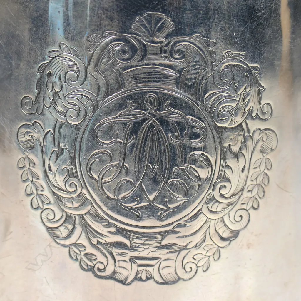 A rare and early George I silver mug -the plain body with an elaborately framed cartouche enclosing scripted initials. Double scroll handle. H.110mm. London 1716 by William Fleming a noted mug maker. 296grms. Image 1++