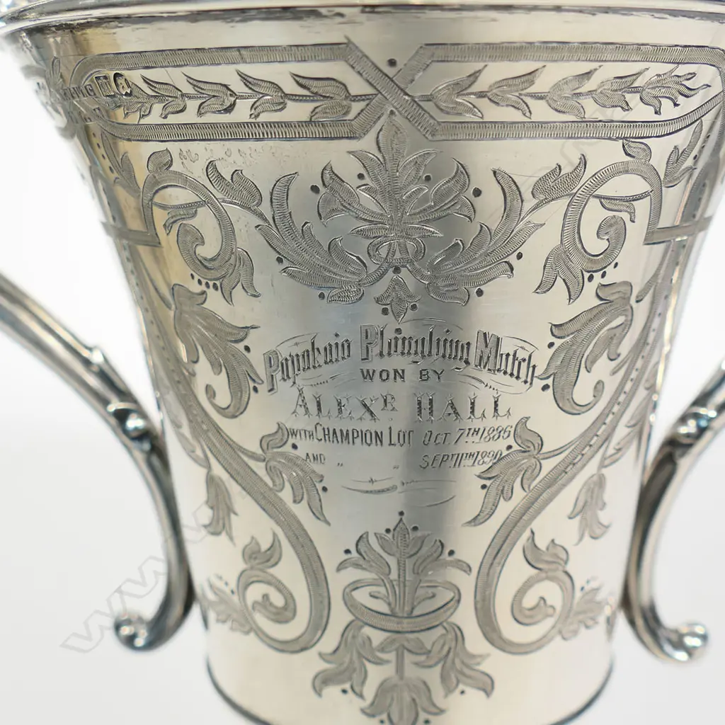 The New Zealand historic 1886 and 1890 silver 'Papakaio Ploughing Match' trophy cup - 'Won by AlexR. Hall'. Engraved to the reverse 'CUP For Champion Lot On Field to Be Won Twice by Same Competitor'. Large scrolling handles. Edinburgh 1882 for G & T Young Dunedin. H.325mm. 523gms. With stand. Image 1++