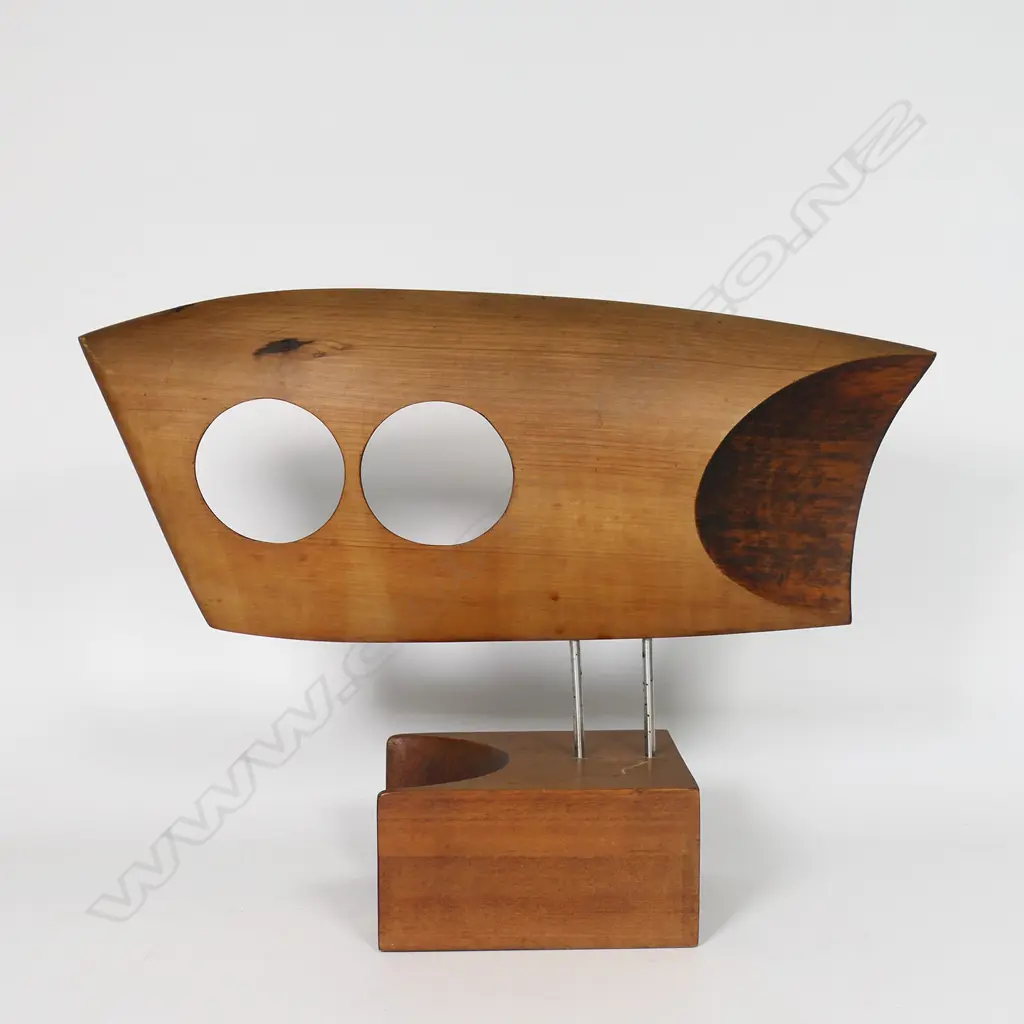 Rex Homan (1940-) carved wooden modernist sculpture. L.380mm, two circular (owls eyes) piercings, raised on two stainless rods (legs) on carved base. Note: Homan was the recipient of the Supreme Award from TE WAKA TOI in 2019 for leadership, excellence of work and outstanding contribution to NGA TOI MAORI globally. Affiliated to three IWI Rex describes his style as Pacific with a contemporary edge. Committed to the power of minimalism he strives for a hint of realism. Image 1++