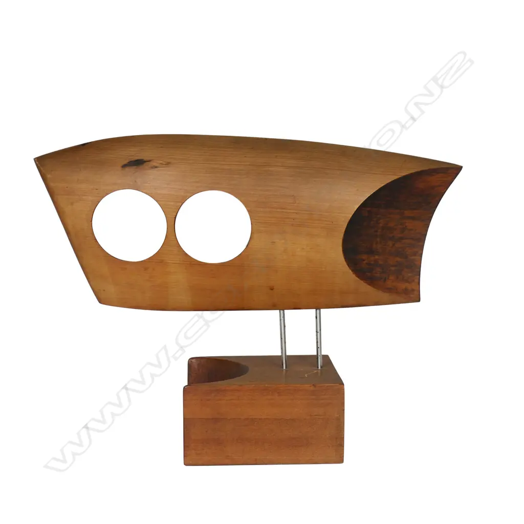 Rex Homan (1940-) carved wooden modernist sculpture. L.380mm, two circular (owls eyes) piercings, raised on two stainless rods (legs) on carved base. Note: Homan was the recipient of the Supreme Award from TE WAKA TOI in 2019 for leadership, excellence of work and outstanding contribution to NGA TOI MAORI globally. Affiliated to three IWI Rex describes his style as Pacific with a contemporary edge. Committed to the power of minimalism he strives for a hint of realism. Image 1++