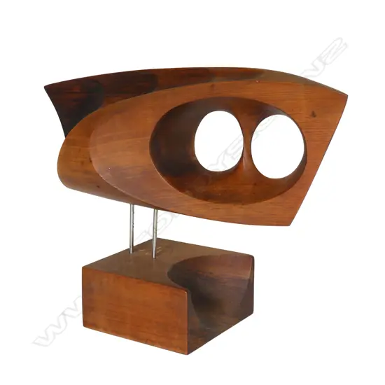 Rex Homan (1940-) carved wooden modernist sculpture. L.380mm, two circular (owls eyes) piercings, raised on two stainless rods (legs) on carved base. Note: Homan was the recipient of the Supreme Award from TE WAKA TOI in 2019 for leadership, excellence of work and outstanding contribution to NGA TOI MAORI globally. Affiliated to three IWI Rex describes his style as Pacific with a contemporary edge. Committed to the power of minimalism he strives for a hint of realism.