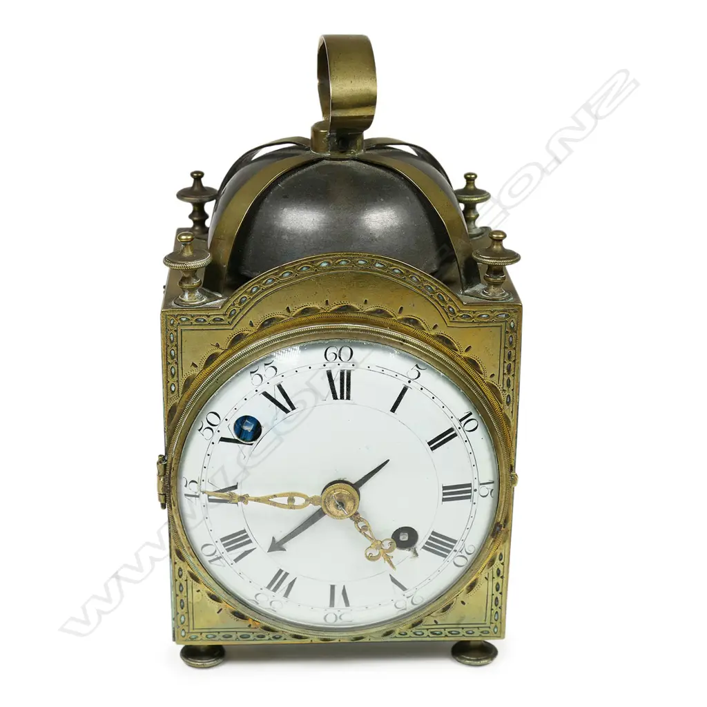 A 19thC brass cased alarm striking lantern clock - the over-head bell supported by four brass cross-over straps secured by the corner finials, convex white enamel dial with Roman numerals. Running, alarm requiring attention. H.150mm. Image 1++