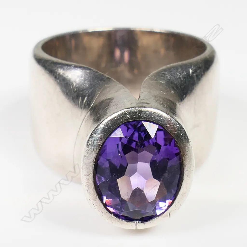 Kobi Bosshard (1939-) modernist silver and amethyst ring - c.1980's, the wide plain band with tall raised top set with an oval facet cut amethyst. Marker's mark to inside band. Note: Kobi Bosshard is recognised as one of New Zealand's founding pioneer studio jewellers.size approx 'M' Image 1++