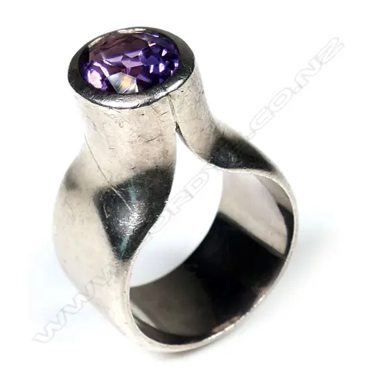 Kobi Bosshard (1939-) modernist silver and amethyst ring - c.1980's, the wide plain band with tall raised top set with an oval facet cut amethyst. Marker's mark to inside band. Note: Kobi Bosshard is recognised as one of New Zealand's founding pioneer studio jewellers.size approx 'M'