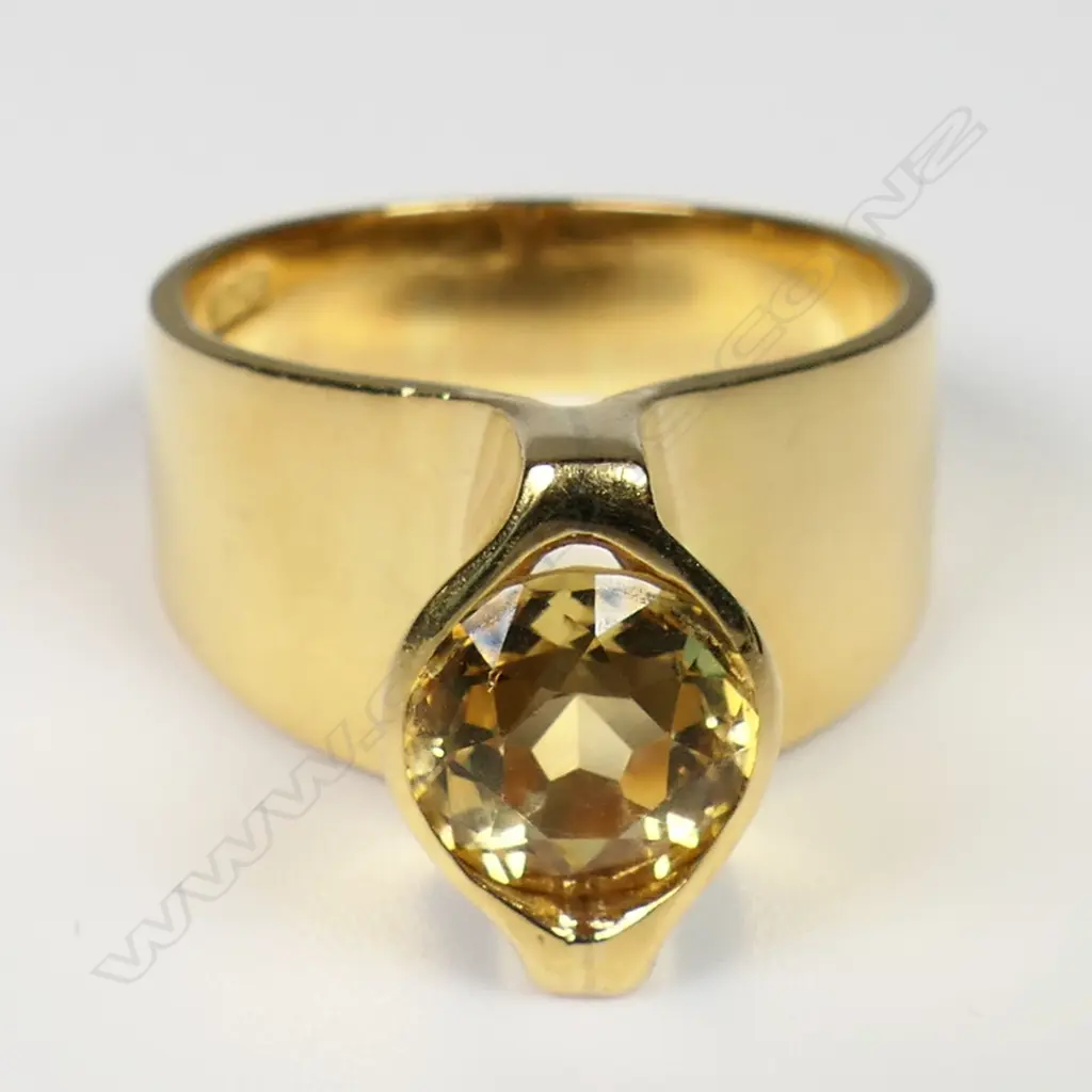 Kobi Bosshard (1939-) modernist 18ct yellow and citrine ring - c.1980's/90's, the wide plain mildly tapered band with tall raised top set with an oval facet cut citrine. Marker's mark to inside band. 11.35gms. Note: Kobi Bosshard is recognised as one of New Zealand's founding pioneer studio jewellers. Size P Image 1++