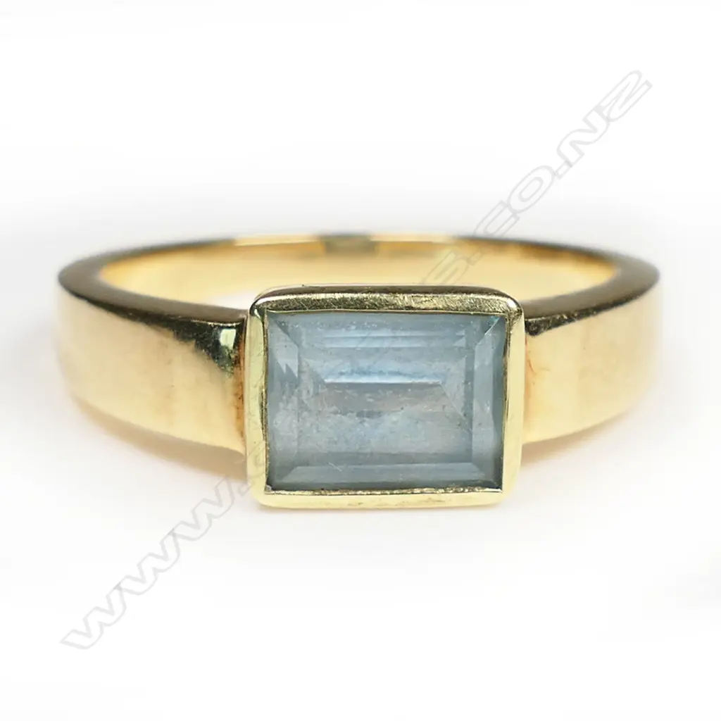 A 14ct yellow gold and blue topaz modern design pendant and ring set - the pendant with three large oval facet cut blue topaz each with rub-over mount set in a vertical row with tubular suspension above. The ring of conforming plain design with single emerald cut blue topaz in rub-over mount. 8.93gms and 5.83gms. 14.76gms total. Image 1++