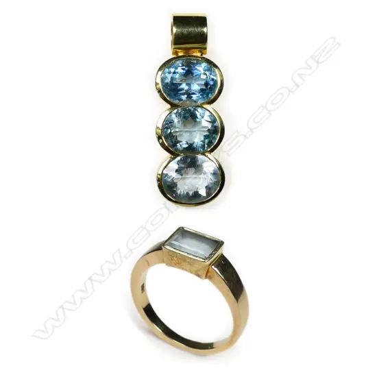A 14ct yellow gold and blue topaz modern design pendant and ring set - the pendant with three large oval facet cut blue topaz each with rub-over mount set in a vertical row with tubular suspension above. The ring of conforming plain design with single emerald cut blue topaz in rub-over mount. 8.93gms and 5.83gms. 14.76gms total.