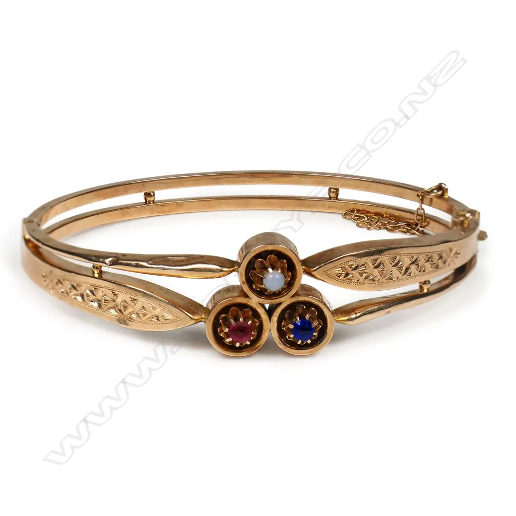 An Edwardian 15ct rose gold hinged bangle - the centre top with three circles multi claw set with gemstones, the bangle formed by two hollow bands, one wide with engraved decoration. Push clasp with safety chain. 9.6gms. Image 1++