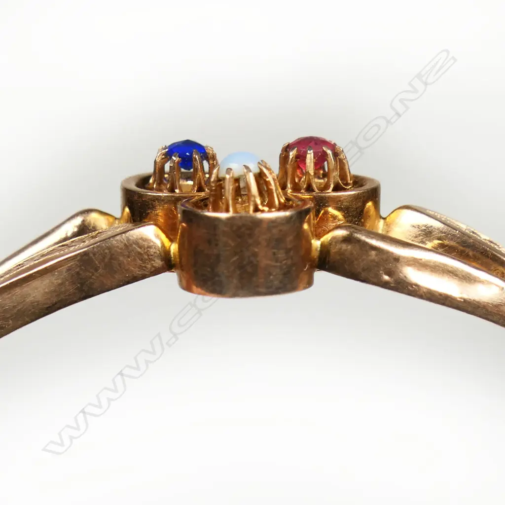 An Edwardian 15ct rose gold hinged bangle - the centre top with three circles multi claw set with gemstones, the bangle formed by two hollow bands, one wide with engraved decoration. Push clasp with safety chain. 9.6gms. Image 1++