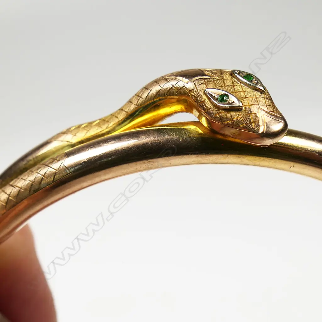 An early 20thC 9ct rose gold snake 'slave' bangle - the snake's head with emerald set eyes. Dia.86mm. 14.38gms. Image 1++