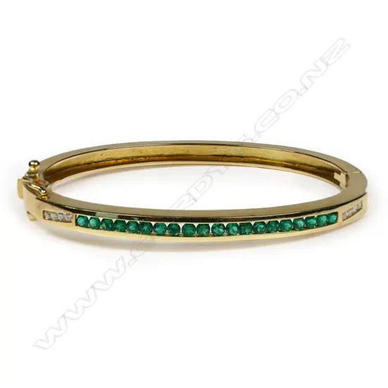 An 18ct gold, emerald and diamond hinged bangle - the top set with twenty small facet cut emeralds of top quality, set between four round brilliant cut diamonds, push clasp with two safety catches. Not marked but tests as 18ct. 15.44gms.