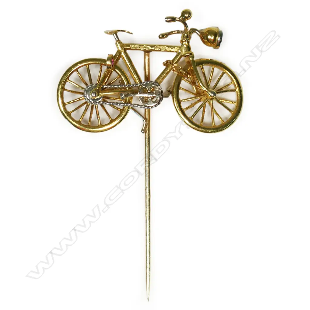 An 18ct yellow gold articulated bicycle pin - set with a modern brilliant cut diamond headlamp and a ruby tail light. L.32.8mm. 5.2gms. Valuation available. Image 1++
