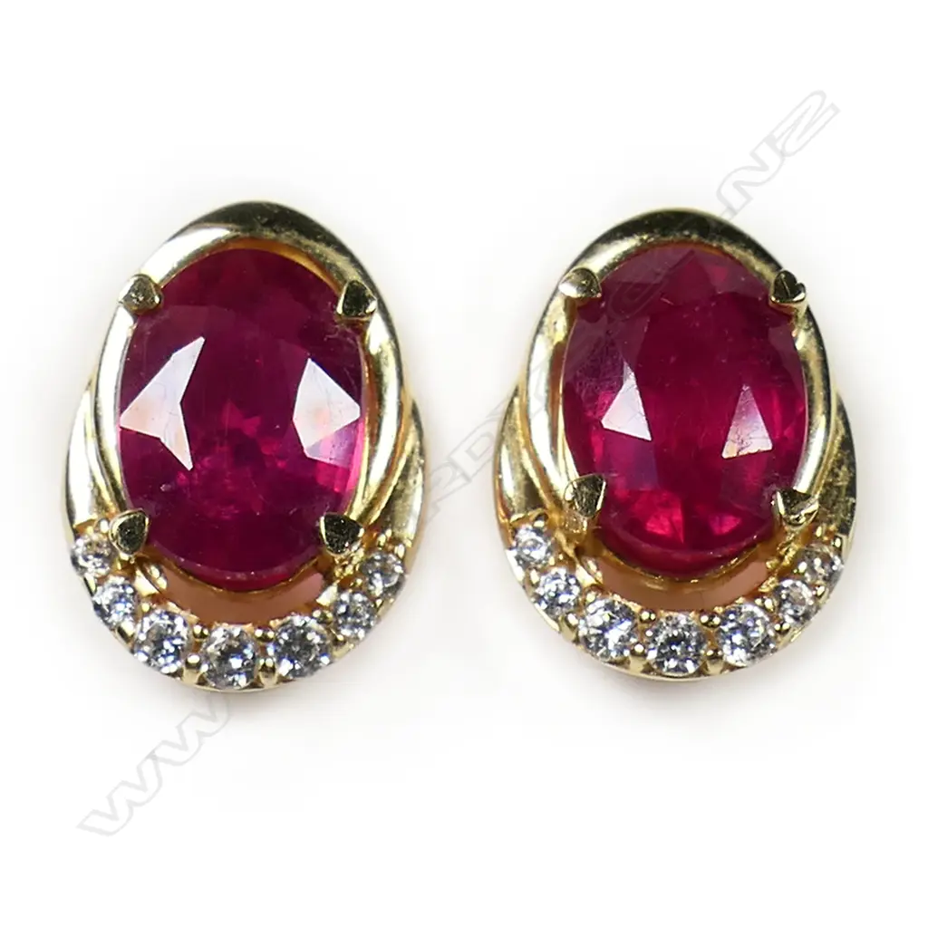 A pair of 18ct yellow gold ruby and diamond earrings - the oval facet cut rubies of good bright tone and clarity, with a curve of seven diamonds to one end and a plain gold curve the other. Fittings for pierced ears. 2.97gms. Image 1++