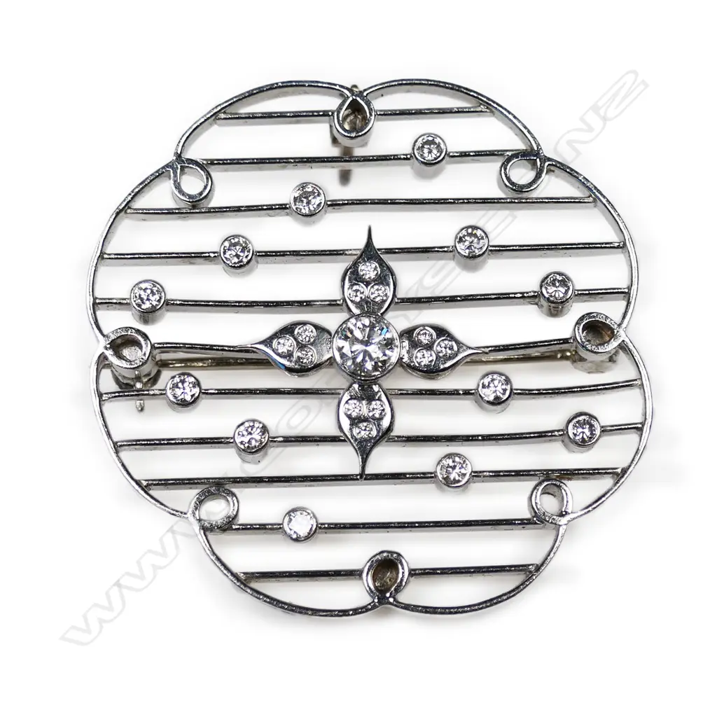 An 18ct white gold and diamond pendant/brooch - the circular flower shaped frame has interior loops with connecting horizontal bars set with small round brilliant cut diamonds (Colour G-I, Clarity VS-SI), to the centre of the frame are four diamond set petals with a 0.25ct round brilliant cut diamond to the centre (Colour H-I, Clarity SI1). TDW. 0.75ct. Pin to wear as a brooch and hinged loop to wear as a pendant. Image 1++