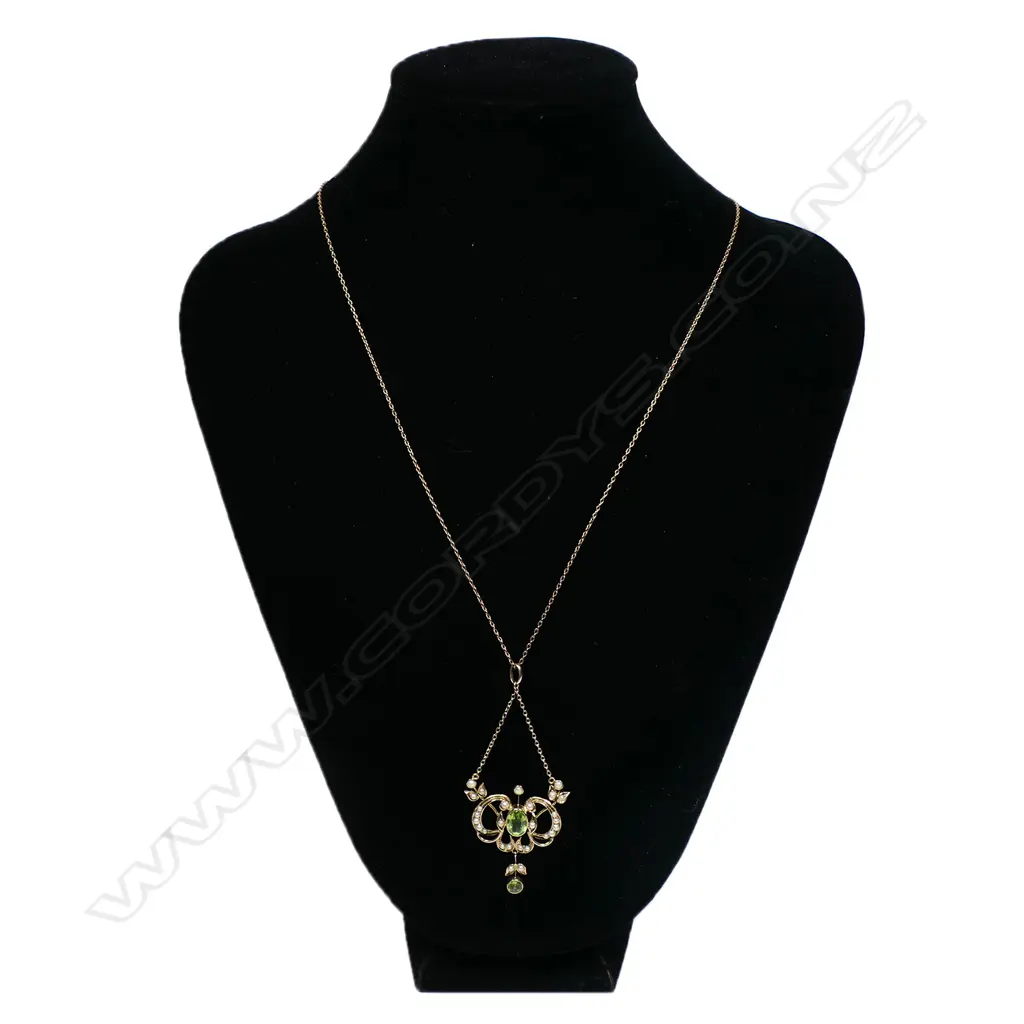 A 9ct gold Edwardian pendant - the floral and leaf frame set with seed pearls , a peridot to the centre with a smaller peridot suspended from base. With very fine 9ct rose gold chain (metal hook and eye clasp). 4.8gms. Image 1++